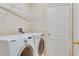 Modern laundry room featuring side-by-side washer and dryer with overhead shelving at 416 Durham Shore Ct, Apollo Beach, FL 33572