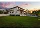 Expansive backyard featuring lush green grass, a pool, and a modern house against a colorful sunset sky at 4300 Bayshore Ne Blvd, St Petersburg, FL 33703