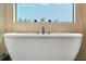 Freestanding tub featuring modern faucet fixtures with textured wall and natural light at 4300 Bayshore Ne Blvd, St Petersburg, FL 33703
