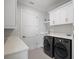 Functional laundry room features matching front load washer and dryer, white cabinets, and modern finishes at 4300 Bayshore Ne Blvd, St Petersburg, FL 33703