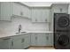 Well-organized laundry room with sage green cabinetry, white countertop, and stacked washer and dryer units at 4300 Bayshore Ne Blvd, St Petersburg, FL 33703
