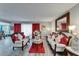 A living room with a white sofa and chair set, gray walls, gray wood floors, red curtains, and a marble table at 4709 Puritan Cir # 702, Tampa, FL 33617