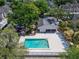 Aerial view of community pool with lounge chairs and adjacent covered area and mature landscaping at 4709 Puritan Cir # 702, Tampa, FL 33617