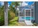 Backyard view featuring a screened-in pool with colorful flowers and mature trees at 4761 Stoneview Cir, Oldsmar, FL 34677