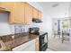 Well-lit kitchen with wood cabinets, granite countertops, black appliances, and an adjacent dining area at 4858 Coquina Key Se Dr # C, St Petersburg, FL 33705
