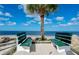 Scenic beach view with two benches near a palm tree and clear blue water at 5047 Bonito Dr, New Port Richey, FL 34652