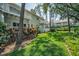 Green backyard with lawn surrounded by trees, shrubs, and condo balconies at 5115 S Jules Verne Ct, Tampa, FL 33611