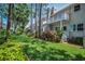 Scenic backyard featuring green grass, shrubs, and condo balconies above at 5115 S Jules Verne Ct, Tampa, FL 33611