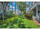 Green backyard with manicured lawn surrounded by trees, shrubs, and condos at 5115 S Jules Verne Ct, Tampa, FL 33611