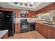 Kitchen featuring brick floors, wood cabinets, and black appliances at 5115 S Jules Verne Ct, Tampa, FL 33611