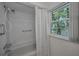 Bathroom featuring shower and tub combination with hand-held shower and a view to the outside at 5115 S Jules Verne Ct, Tampa, FL 33611