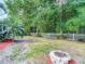 Spacious backyard featuring lush greenery, mature trees, and a charming fire pit at 5143 New Brittany Ln, Zephyrhills, FL 33541