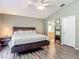 Main bedroom with a wooden headboard bed, ceiling fan, and ensuite bathroom with walk-in closet at 5143 New Brittany Ln, Zephyrhills, FL 33541