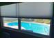 View of sparkling blue pool through a window offering a glimpse of the landscaped backyard at 101 Madonna Blvd, St Petersburg, FL 33715