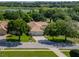 Beautiful aerial view of a well-maintained home with a tile roof surrounded by lush trees and a pristine lawn at 12902 Grand Traverse Dr, Dade City, FL 33525