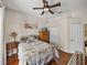 Bedroom has wood floors, ceiling fan, beach artwork, closet, and hall access at 12902 Grand Traverse Dr, Dade City, FL 33525