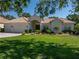 Charming single-story home featuring a well-manicured lawn, lush landscaping, and a tile roof at 12902 Grand Traverse Dr, Dade City, FL 33525