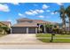 Beautiful two-story home with a three-car garage, a well-maintained lawn, and mature palm trees at 12925 Tar Flower Dr, Tampa, FL 33626