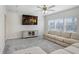 Living room with a ceiling fan, plush neutral-colored sofa, and a media center beneath a wall-mounted television at 14184 Samoa Hill Ct, Riverview, FL 33569