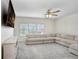 Bright living room featuring a comfortable L-shaped couch, media center and large window with a ceiling fan at 14184 Samoa Hill Ct, Riverview, FL 33569