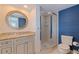 Comfortable bathroom with a walk-in shower, a decorative mirror, and blue textured wall at 1625 Watermark Ne Cir, St Petersburg, FL 33702
