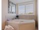 Garden tub with tiled backsplash, white towels, and shuttered window in the en suite Primary bathroom at 1625 Watermark Ne Cir, St Petersburg, FL 33702