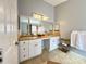 Bright bathroom featuring a double sink vanity with granite countertops, a large mirror, and modern lighting fixtures at 1813 Landside Dr, Valrico, FL 33594