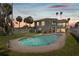 Backyard oasis with a sparkling pool surrounded by lush landscaping and palm trees at sunset at 1842 Bayou Grande Ne Blvd, St Petersburg, FL 33703