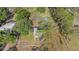 Aerial view showcases a home nestled within large trees, with a fenced yard and additional buildings nearby at 18838 Huckavalle Rd, Odessa, FL 33556