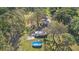 Aerial view of a home with a backyard pool, covered patio, mature trees, and green landscaping at 18838 Huckavalle Rd, Odessa, FL 33556