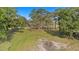 Wide aerial view of the property and house, surrounded by mature trees and a bright green lawn at 18838 Huckavalle Rd, Odessa, FL 33556
