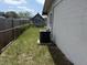 View of home's side and backyard with patchy grass, AC unit, and chain link fence at 1905 Meridel Ave, Tampa, FL 33612