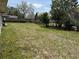 View of disrepaired backyard featuring grassy area with fence line and mature trees at 1905 Meridel Ave, Tampa, FL 33612