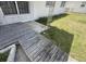 Shows part of a side yard with overgrown grass and deteriorating wooden deck abutting the home's facade at 1905 Meridel Ave, Tampa, FL 33612