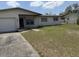 Exterior shot of house with garage and overgrown lawn and driveway at 1905 Meridel Ave, Tampa, FL 33612