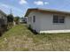Exterior view of home with three windows along side and small yard in disrepair at 1905 Meridel Ave, Tampa, FL 33612