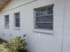 House exterior featuring a stucco wall with windows and overgrown yard at 1905 Meridel Ave, Tampa, FL 33612