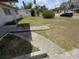 Depicts the unkempt front yard, including a deteriorated wood deck and overgrown grass at 1905 Meridel Ave, Tampa, FL 33612