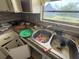 View of cluttered kitchen needing renovation with dated cabinets and stainless steel sink at 1905 Meridel Ave, Tampa, FL 33612