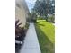 Long concrete walkway with green grass and colorful landscaping leading along the side of the property at 2007 Acadia Greens Dr # 0, Sun City Center, FL 33573