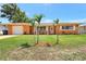 A well-maintained, single-story home with a lush green lawn and small palm trees at 3065 Merrill Ave, Clearwater, FL 33759
