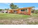 Charming, single-story home featuring an orange exterior, white trim, manicured lawn, and delightful landscaping at 3065 Merrill Ave, Clearwater, FL 33759