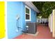 Exterior side view of blue house with brick pavers leading to yellow door and white fence at 3306 E Chelsea St, Tampa, FL 33610