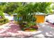 Charming home with lush palm trees, bright yellow garage door, and a colorful brick driveway at 3306 E Chelsea St, Tampa, FL 33610