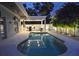 Backyard pool at dusk with covered outdoor kitchen, bar, and seating at 413 8Th N Ave, Tierra Verde, FL 33715
