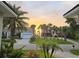 Scenic street view featuring a home with palm trees, lush lawn, and a picturesque sunset backdrop at 413 8Th N Ave, Tierra Verde, FL 33715
