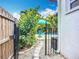 View of backyard gate, pool, and lounge furniture through lush landscaping at 4231 8Th N St, St Petersburg, FL 33703