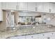 Bright kitchen featuring granite countertops, white cabinetry, and open view to the living and dining areas at 425 150Th Ave # 2301, Madeira Beach, FL 33708