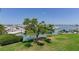Scenic waterfront view with lush green grass, a mature tree, and boats docked in the background at 425 150Th Ave # 2301, Madeira Beach, FL 33708
