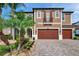 Two-story home with a brick driveway, palm trees, a two-car garage, and an iron-wrought Juliette balcony at 4419 Ortona Ln, Wesley Chapel, FL 33543